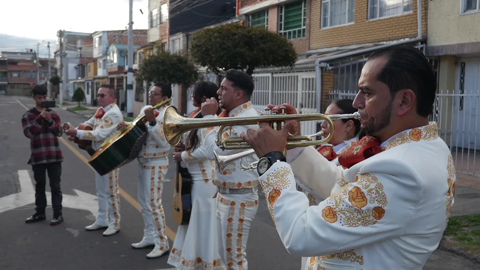Mariachis tocando en la calle de un barrio de Soacha con los vecinos alrededor